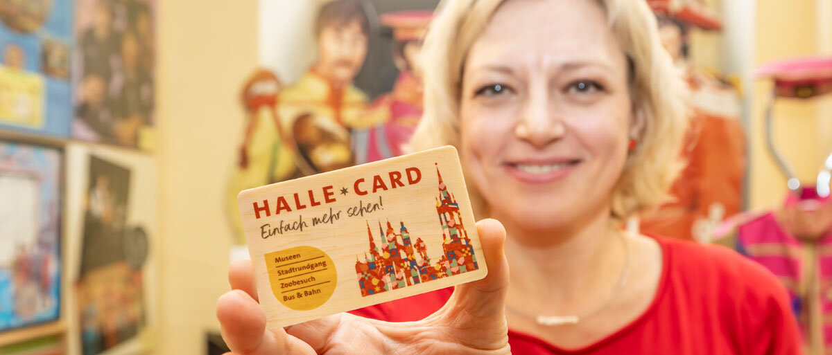 Eine Mitarbeiterin der SMG hält eine Halle-Card aus Holz